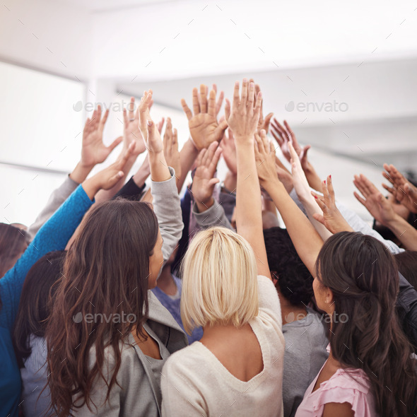 Shot of a business team raising their hands while standing in a huddle