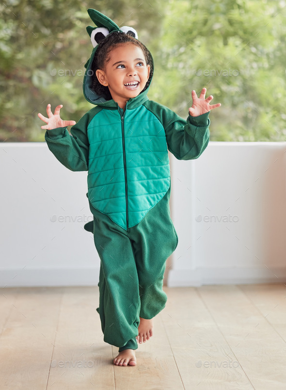 Child, smile and excited in halloween dinosaur costume at home playing role and having fun at party