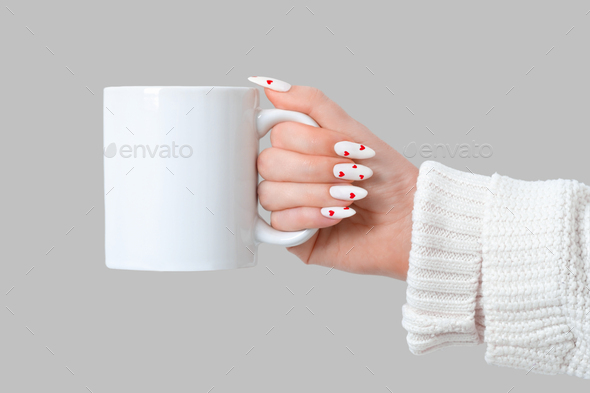 Female hands hold mock up white empty mug on a gray background, cup for  Valentine's Day manicure Stock Photo by marykor_ua