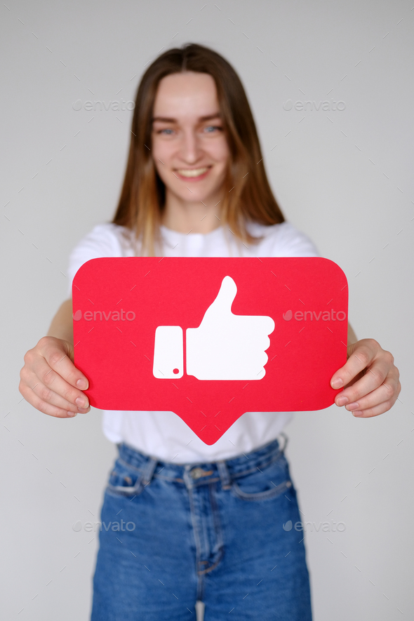 Cheerful carefree woman holding Like button icon of social media