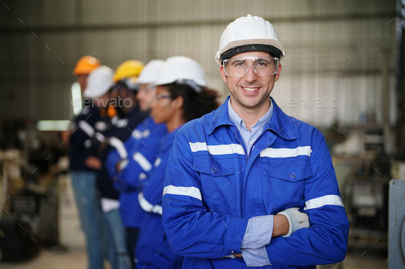 Young confident leader of team standing in front of factory workers - Stock Photo - Images