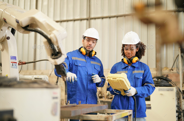 Robotics engineer operating robot aided CNC machine in robotics ...