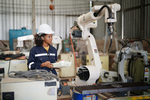 Robotics engineer operating robot aided CNC machine in robotics ...