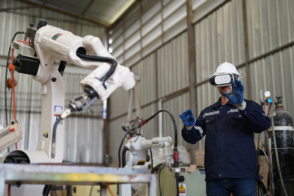 Robotics engineer operating robot aided CNC machine in robotics ...