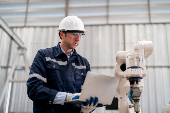 Robotics engineer operating robot aided CNC machine in robotics ...