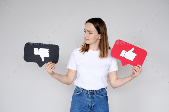 Young woman holding Like button and Dislike button icon of social media