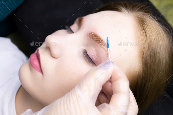 the master combs the eyebrows with a special brush after the eyebrow lamination procedure