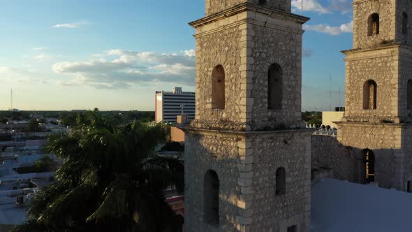 Aerial camera at sunset slipping to the right and rising behind the bell towers of Rectory Jesus (th alt