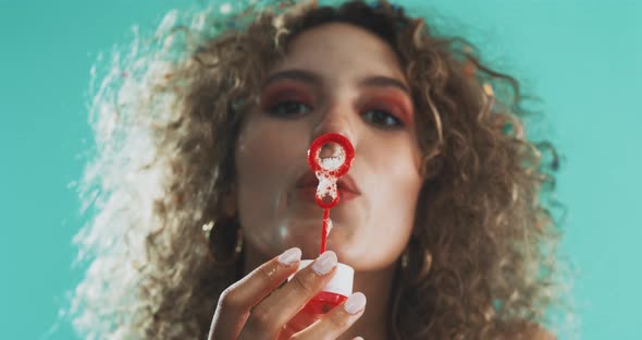 Girl looking at the camera and blowing bubbles alt