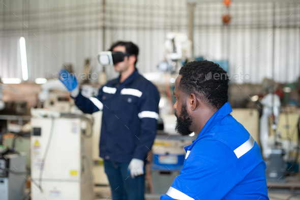 Chief and young male engineer uses a VR machine to operate a welding robot.