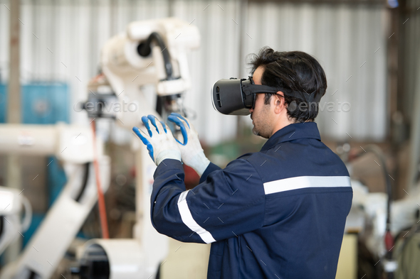 A young male engineer uses a VR machine to operate a welding robot. for precision welding control