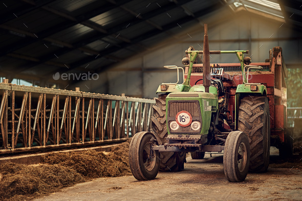 Old faithful. Shot of a rusty old tractor standing in an empty barn.