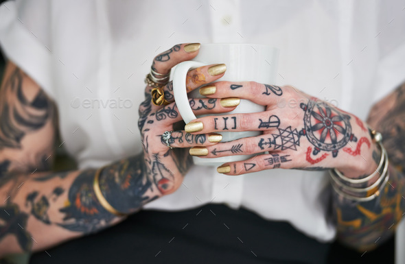 She loves her tattoos. Shot of an unrecognizable tattooed businesswoman holding a mug.