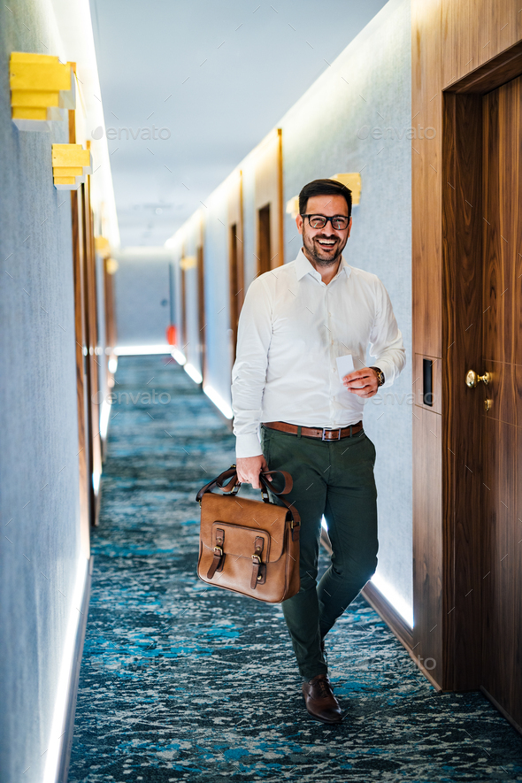 Portrait of a successful businessman in a hallway of a hotel, holding key card and document case. - Stock Photo - Images