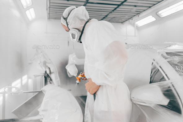 Man painting parts of a car in cars spray booth.