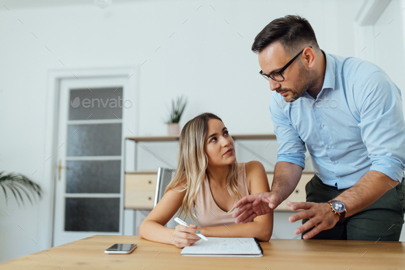 Private tutor explaining something to a female college student, portrait.