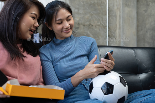Friends watch sports on mobile phone, cheer and celebrate. Happy diverse asian friend supporters