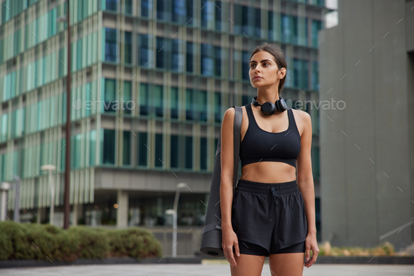 Sport and recreation concept. Self confident slim sportswoman in black cropped top and shorts carrie