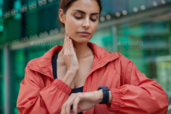 Cropped shot of serious woman checks pulse on neck monitors fitness activity has quick heart rate we