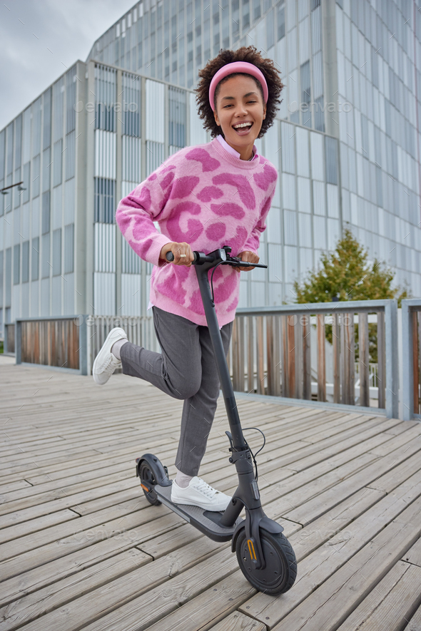 Outdoor activities lifestyle and ecological transport concept. Joyful curly haired young female mode - Stock Photo - Images