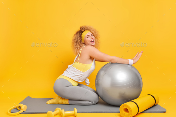 Female fitness model posing with medicine ball at gym. Young