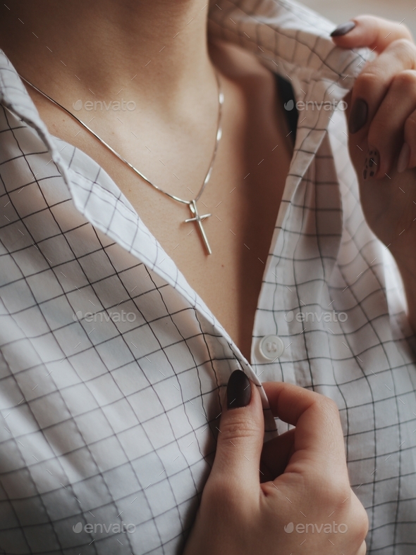 Closeup shot of a female wearing a white shirt and a delicate silver charm necklace