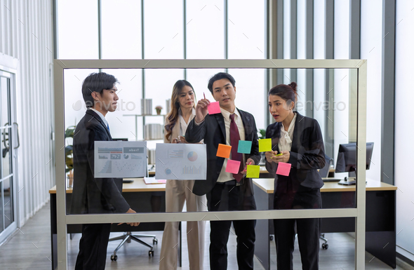 Employee meeting at office and use post it notes to share idea brainstorming stick on glass wall