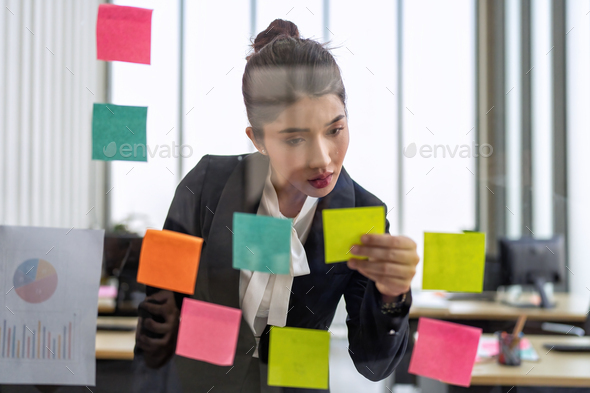 Employee meeting at office and use post it notes to share idea brainstorming stick on glass wall