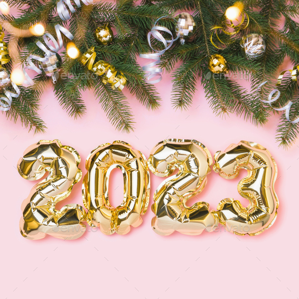 New year 2023 celebration card. Gold balloon number 2023, christmas tree branch, decoration on pink