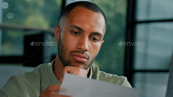 Calm African Latin guy man student entrepreneur open envelope notification from bank test result
