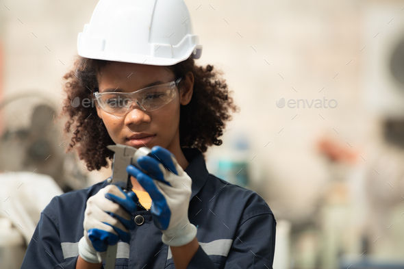 A young female engineer inspects and repairs parts of a robotic welding machine