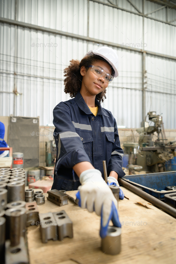 A young female engineer inspects and repairs parts of a robotic welding machine