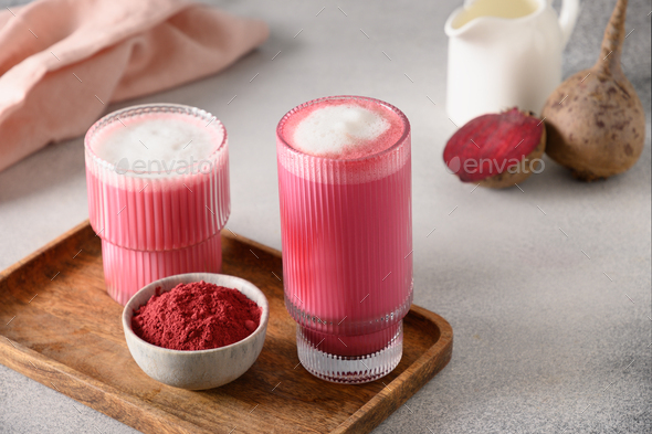 Beetroot latte or pink moon milk latte in glass cup on gray background. Great warming drink.