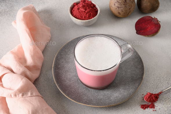 Beetroot latte or pink moon milk latte in glass cup on gray background. Great warming drink.