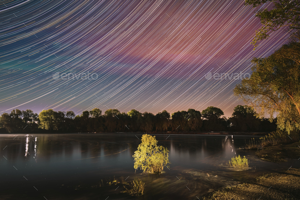 Unusual Stars Effect Sky. Meteors Fly Across Night Sky. Night Sky Above River. From Dusk To Dawn