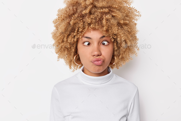 Photo of funny woman makes grimace pouts lips and crosses eyes has childish expression acts like foo