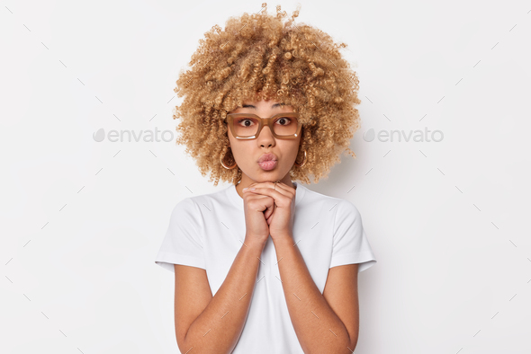 Portrait of good looking young woman keeps hands under chin has folded ...