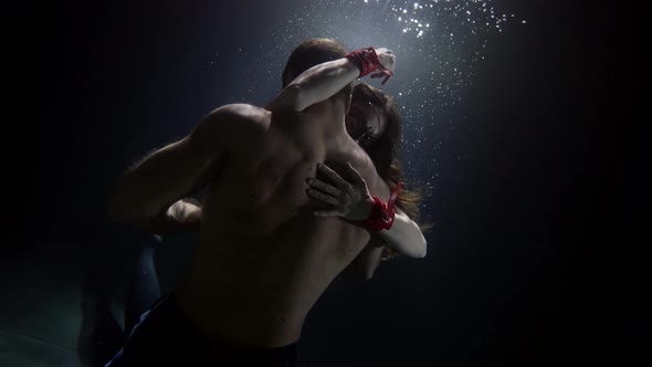 A Man Embraces and Touches His Woman Underwater Lovers Deep Inside on a Dark Background alt