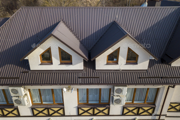 Close-up aerial view of building attic rooms exterior on metal shingle roof