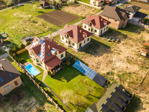 Aerial view of a private house with green grass covered yard, solar panels on roof