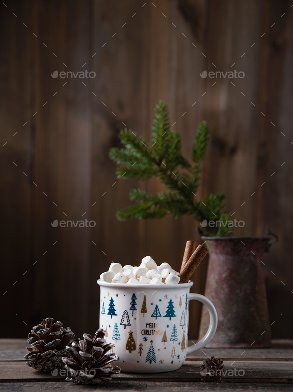 Christmas cup of cacao and marshmallow with cinnamon on an old brown wooden table with cones and fir