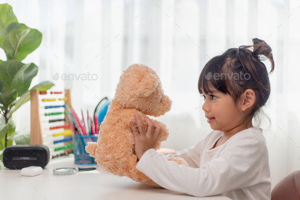 Child playing with teddy bear. Asian little girl hugging his favorite toy.