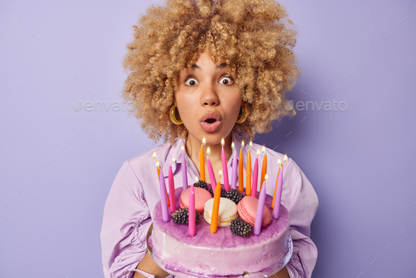 Surprised Curly Haired Woman Blows Candles On Festive Cake Holds Breath