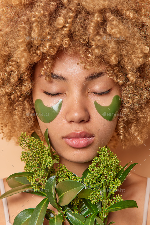 Photo of curly haired young woman with natural skin takes care of
