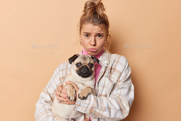 Disappointed frustrated young female pet owner sad because of illness of dog go together to vet clin
