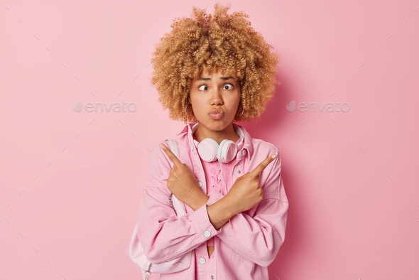 Hesitant confused young woman makes funny grimace tries to make choice crosses hands against chest p