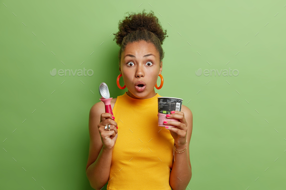 Startled Curly Haired Beautiful Woman Stares Impressed At Camera Keeps Mouth Opened Eats