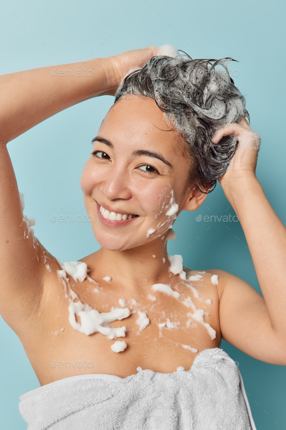 Relaxed Cheerful Asian Woman Washes Head In Foam With Shampoo Poses Half Naked With Soap On Body