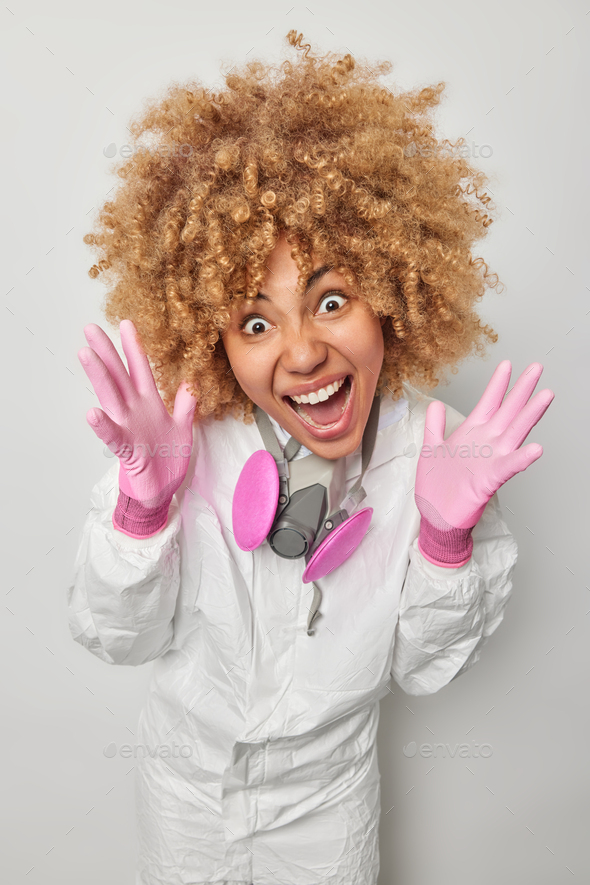 Emotional Young Woman With Curly Hair Keeps Palms Raised Screams Loudly Dressed In Protective 