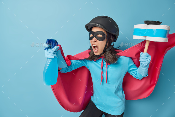 Photo of female superhero shouts loudly ready to help you with cleaning holds spray detergent and pl